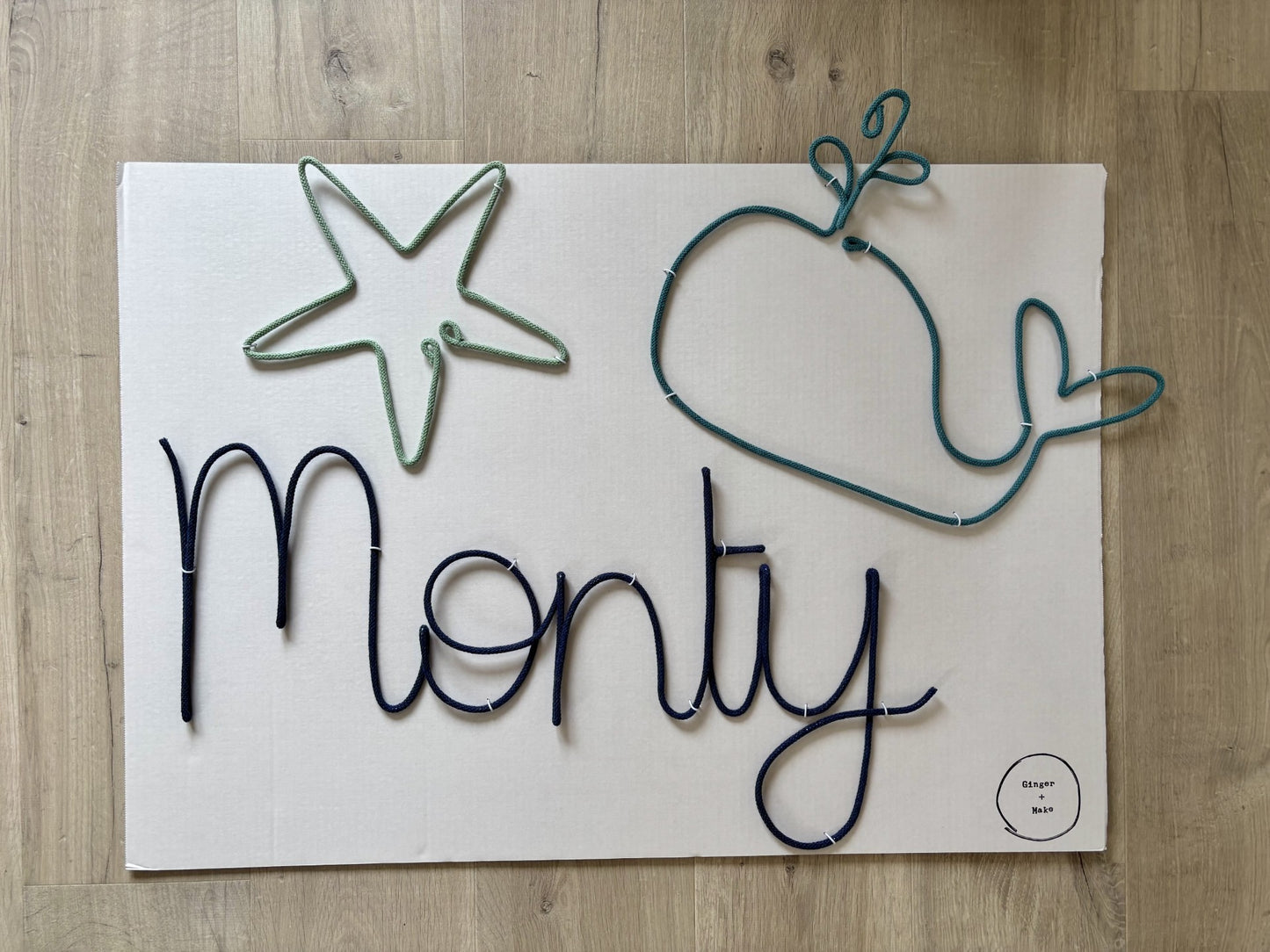Decorative wire sign with wire whale and starfish on a wooden surface