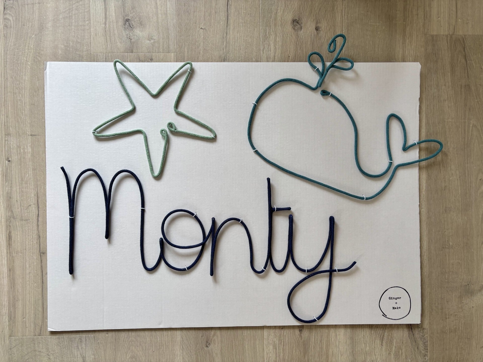 Decorative wire sign with wire whale and starfish on a wooden surface