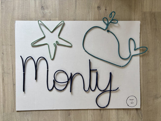Decorative wire sign with wire whale and starfish on a wooden surface