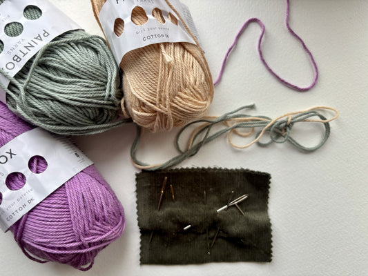Yarn balls in various colors with knitting needles on a white water colour paper surface