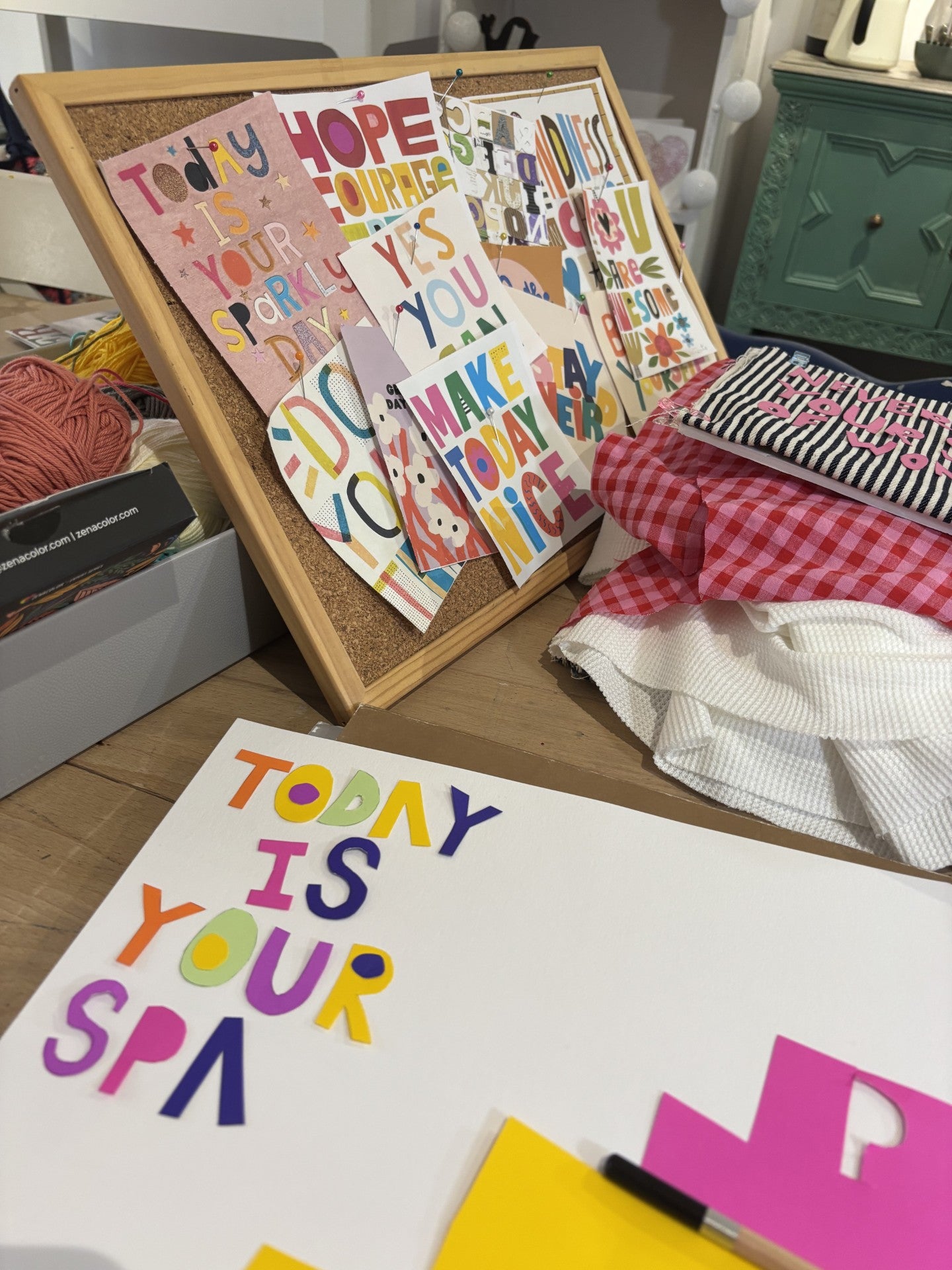 Colorful motivational posters on a cork board with various items in the background.