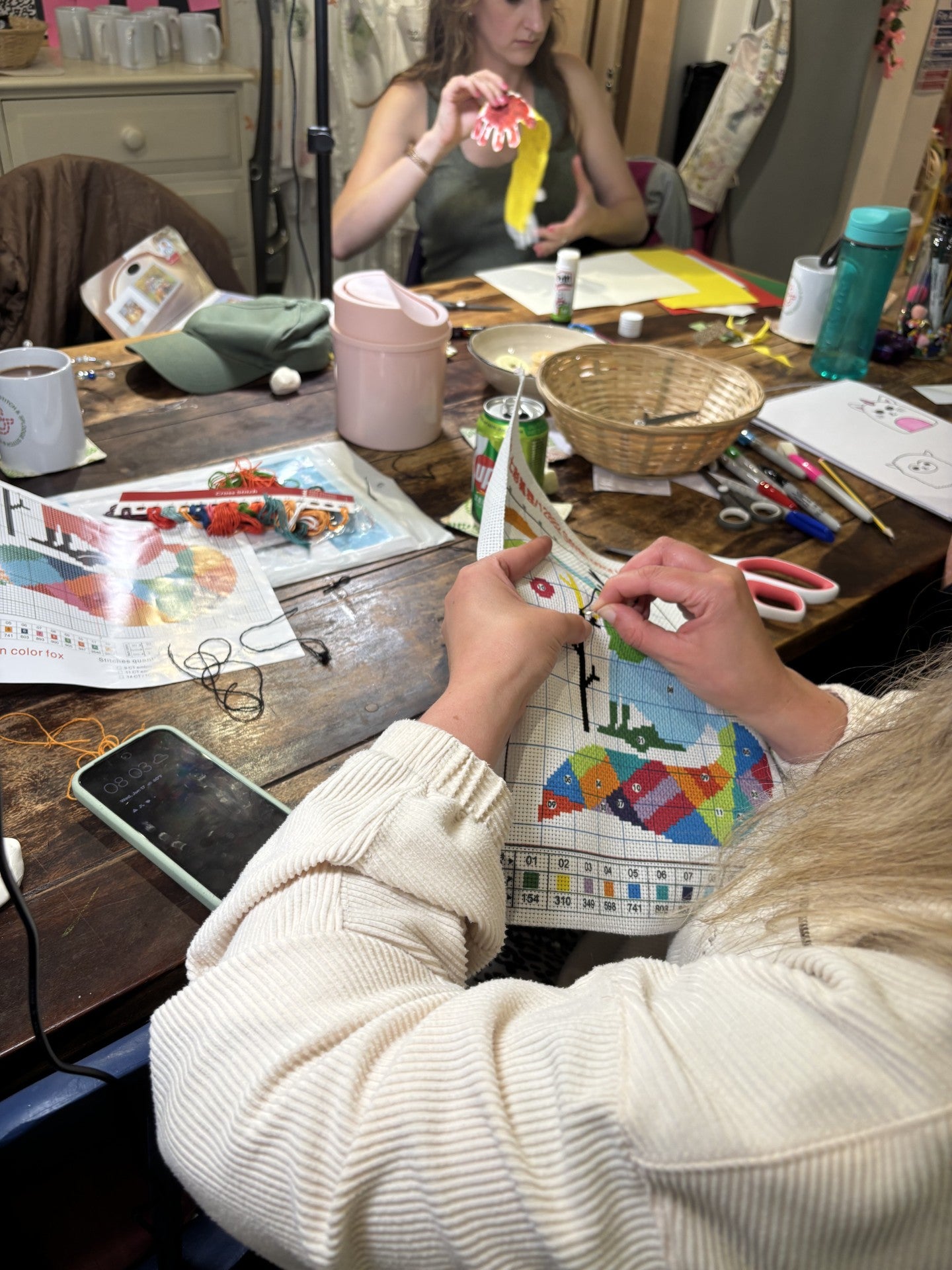 Person working on a craft project at a table with various supplies