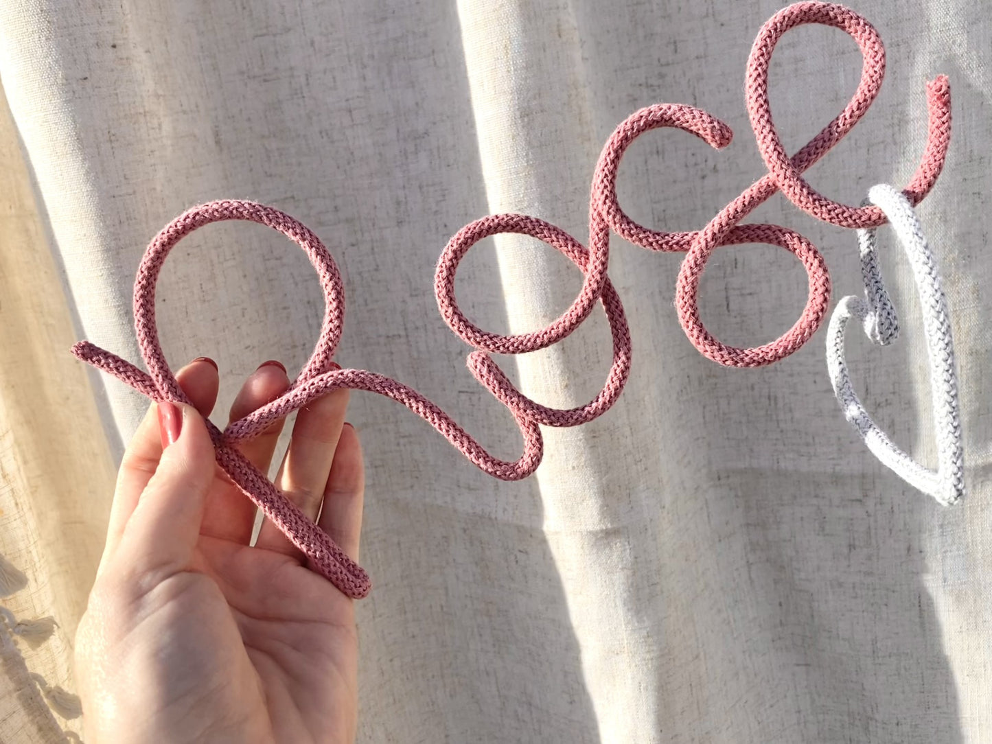 Blossom wire name 'Rose' held by a hand against a neutral background