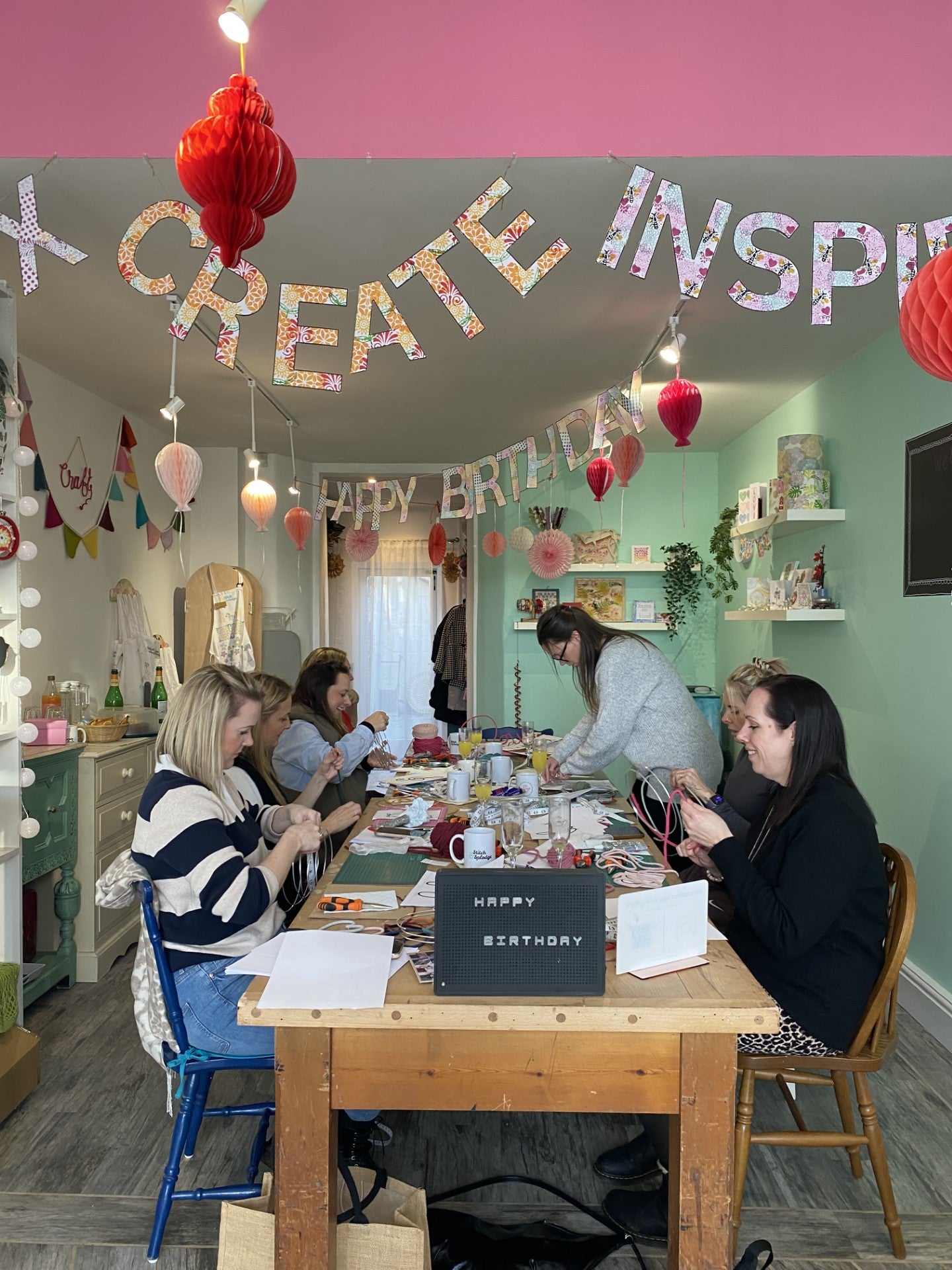 People gathered around a craft table in a room with 'Create Inspire' 