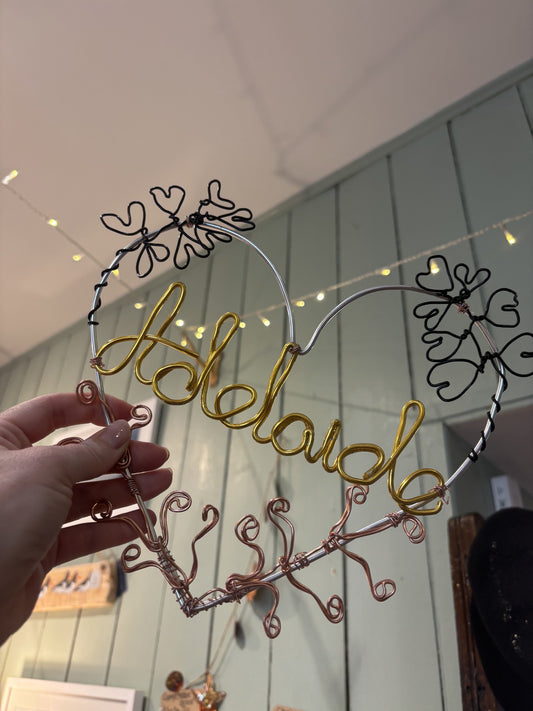 Decorative wire wreath with 'Adelaide' written on it, held by a hand.