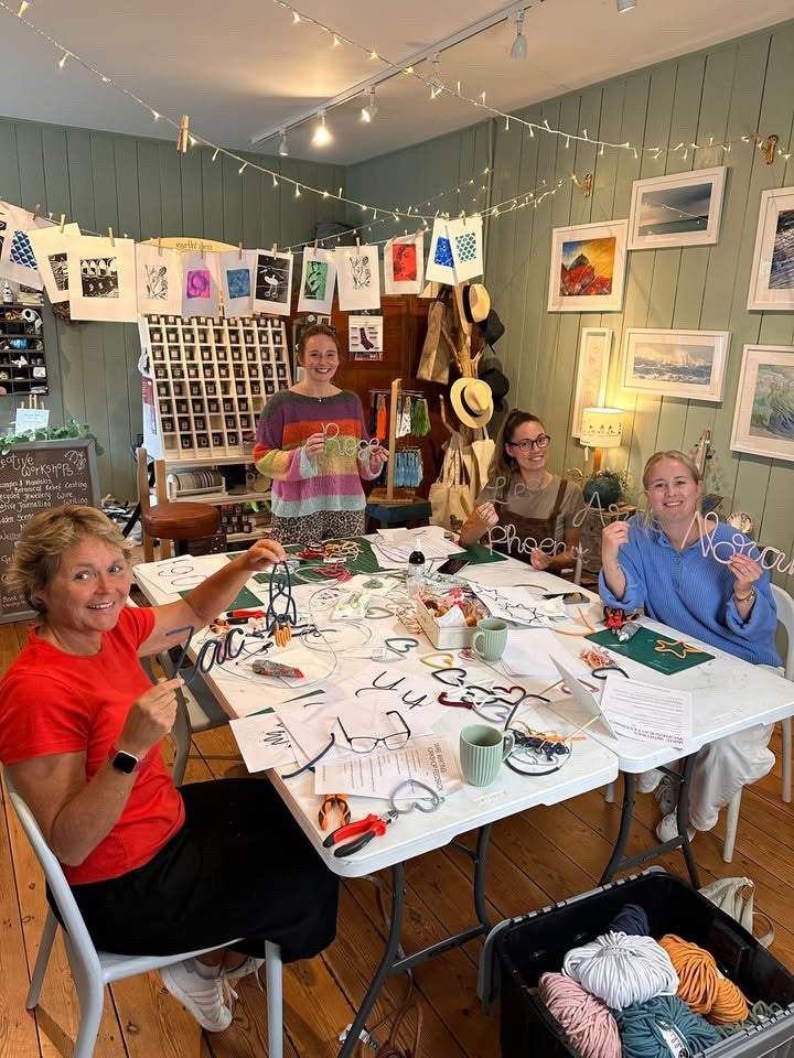 Group of people at a craft workshop with materials and decorations on a table.